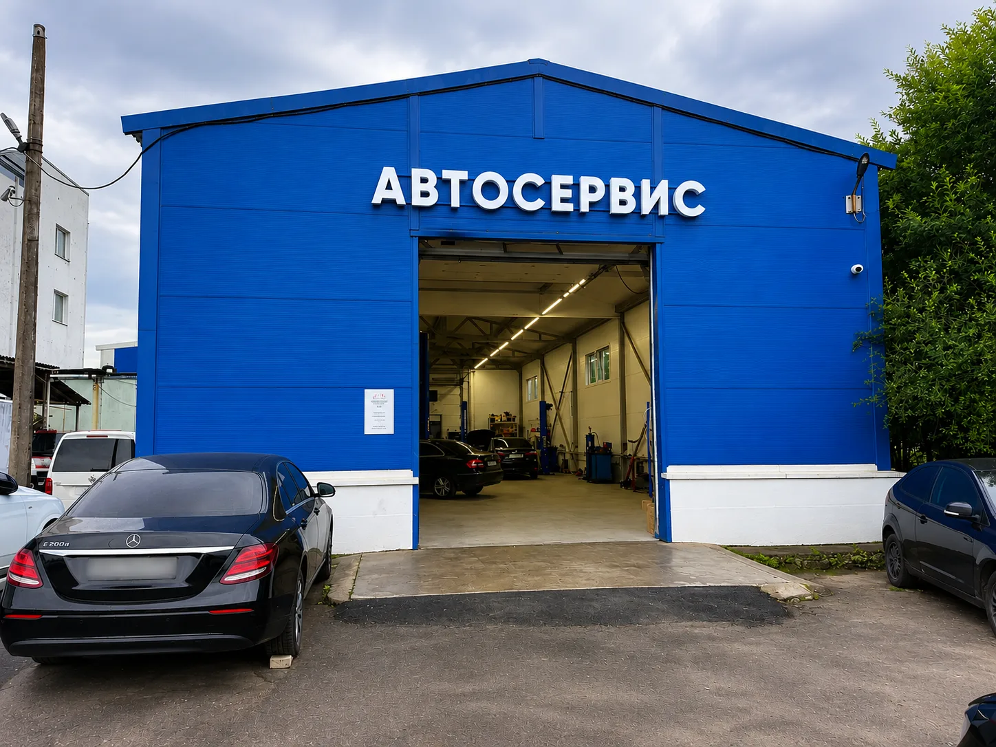 Вход в автосервис СТЭЛ — синий ангар с вывеской «Автосервис» и открытыми воротами ремзоны на ул. Электропультовцев, 7